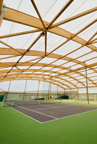 Deux courts de tennis dans un bâtiment en charpente bois