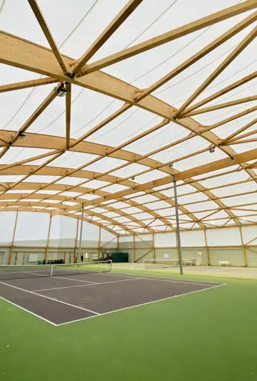 Deux courts de tennis dans un bâtiment en charpente bois