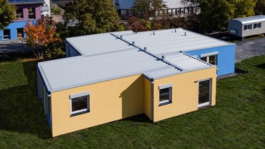 Luftaufnahme modularer Kindergarten mit blau-gelber Putzfassade Losberger Modular Systems 
